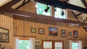 Una sala de estar acogedora con chimenea, paredes de madera y un ventanal grande.
