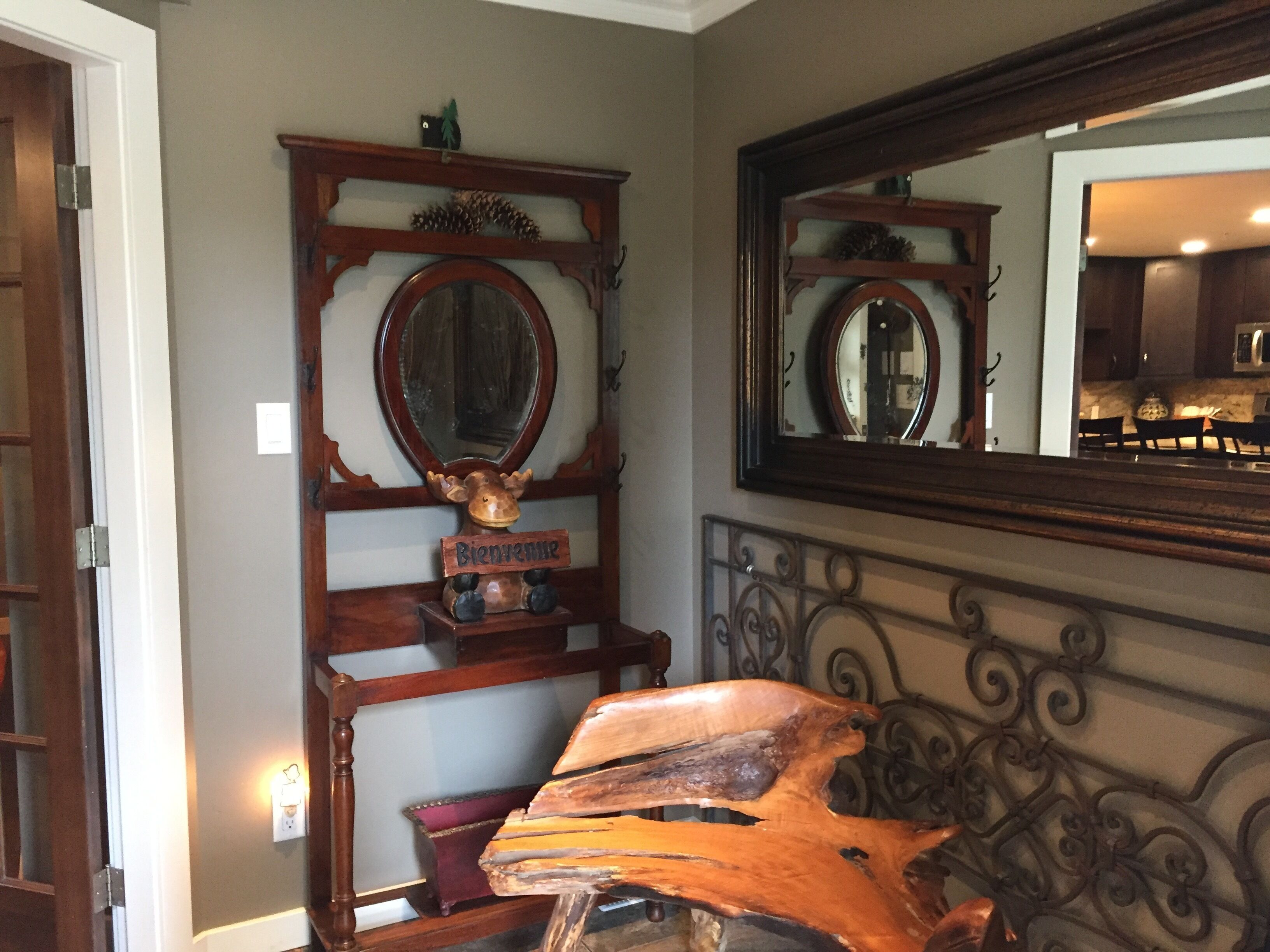 A room with a wooden headboard, a mirror, and a wooden sculpture.