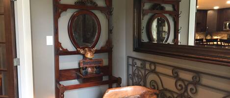 A room with a wooden headboard, a mirror, and a wooden sculpture.