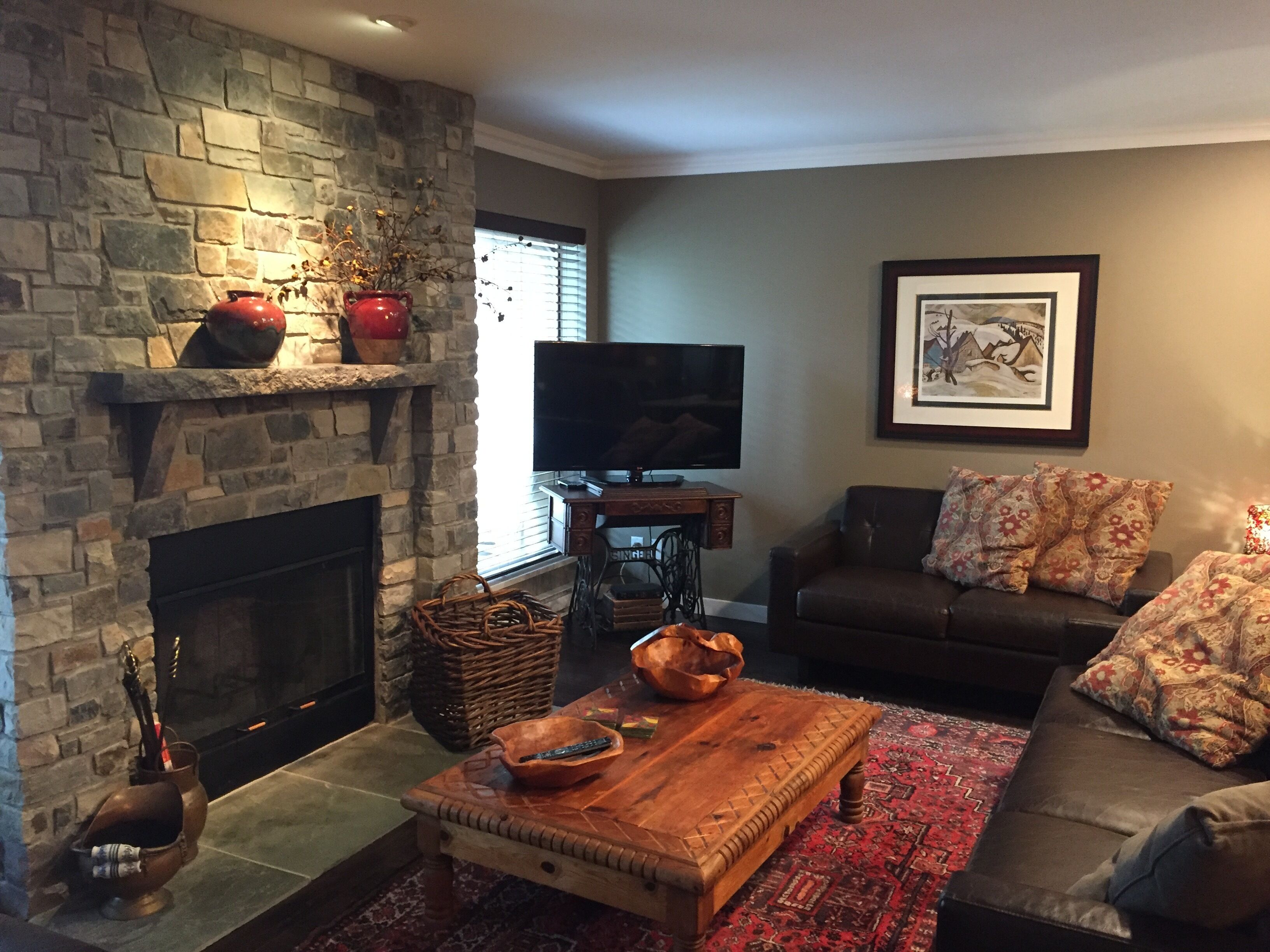 Una sala de estar con chimenea de piedra, televisor, sofá y mesa de centro.