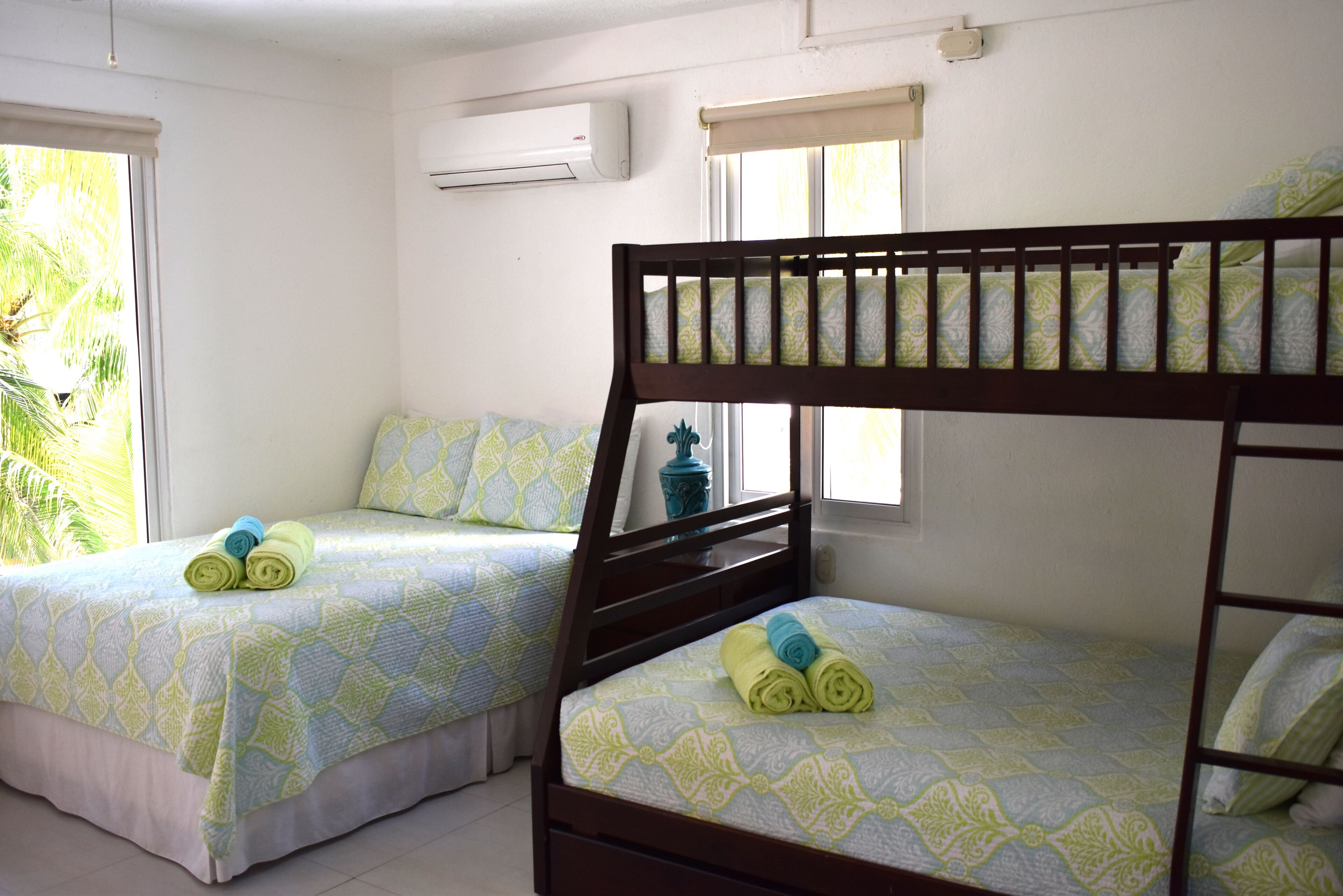 Une chambre avec deux lits superposés, chacun étant agrémenté d’une couverture à motifs et de serviettes enroulées.