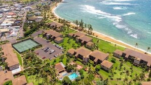 An aerial view of a coastal resort with beachfront villas, a tennis court, and a swimming pool. - Kauai Pono Kai Resort BR/1BA Condominium -- Sleeps 4  (Kapaa)