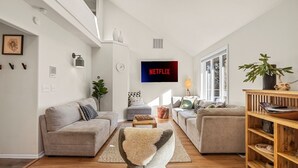 A modern living room with two sofas, a coffee table, a TV, and a bookshelf. - Private 2.5 acres, Hot Tub, Fire Pit, Ping Pong, 10 minutes to town (Underwood)