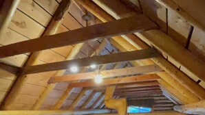 Un dormitorio cálido en el ático con una cama de madera, una mesita y una silla.