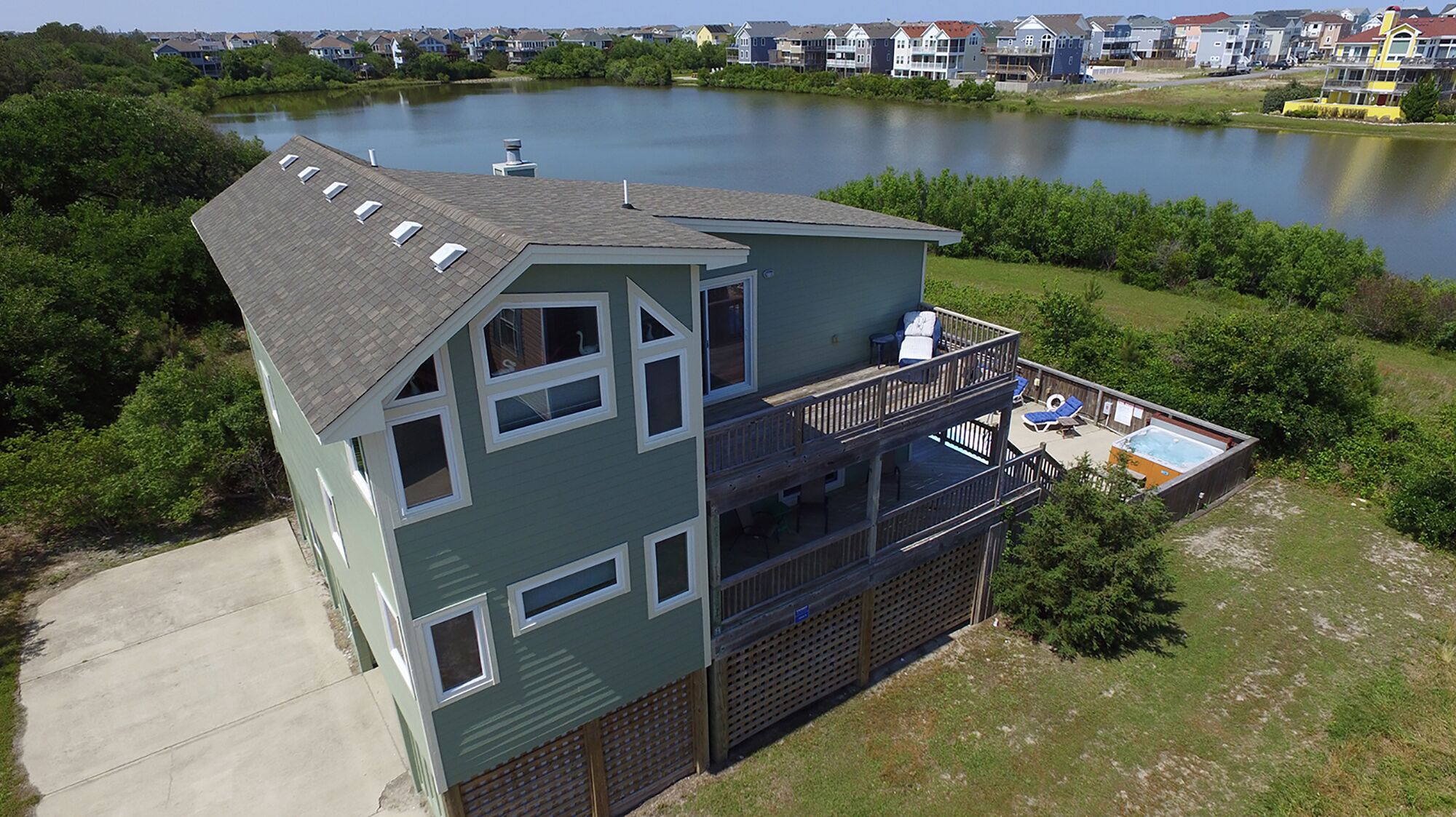 A two-story house with a balcony, a hot tub, and a view of a lake.