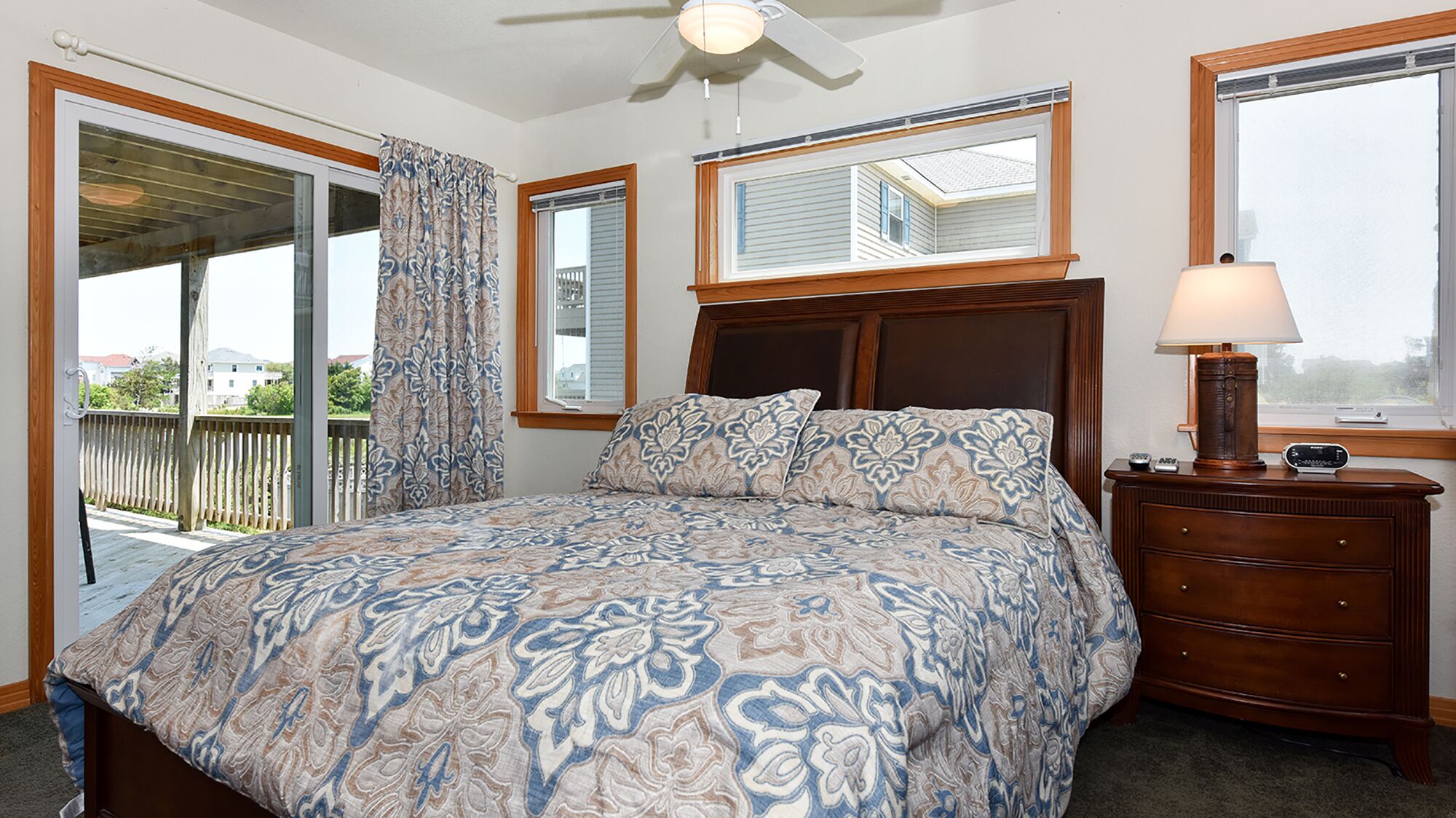 A bedroom with a bed, a dresser, a lamp, and a ceiling fan.