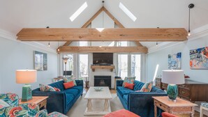 A spacious living room with two blue sofas, a white coffee table, and a fireplace.