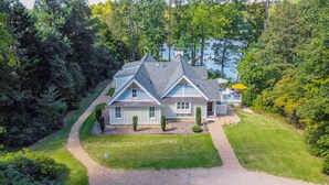 A two-story house with a sloped roof, a front porch, and a small deck.