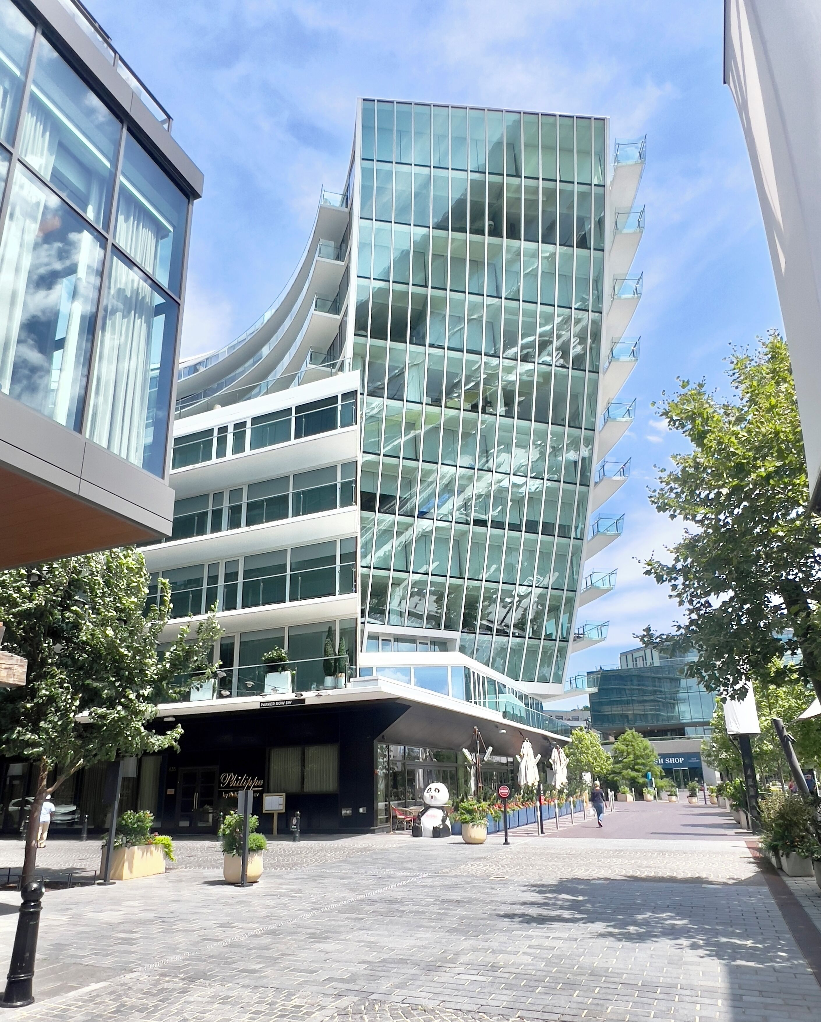 Un bâtiment moderne doté d’une façade en verre et de nombreux balcons.