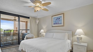 A hotel room with a large bed, two bedside lamps, a ceiling fan, a balcony with a view, and a framed painting on the wall. - First Floor Near the Main Elevators/Stairs and Just Steps From the Pool, Pavilio (Destin)