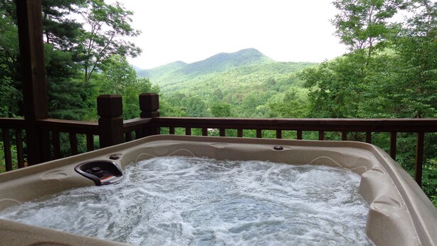 Een hottub met uitzicht op een bebost berglandschap.