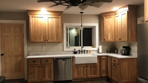 A kitchen with wooden cabinets, a dishwasher, a sink, and a ceiling fan. - Private 150-Acre Farmhouse near Universities (Colton)