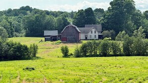 A rural landscape with a barn, a white house, and a green field. - Private 150-Acre Farmhouse near Universities (Colton)