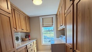 A kitchen with wooden cabinets, a window, and a white refrigerator. - Private 150-Acre Farmhouse near Universities (Colton)