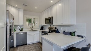 Une cuisine moderne avec des meubles blancs, des appareils en acier inoxydable et un îlot central.