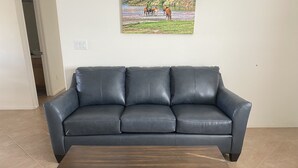 A dark leather sofa and a wooden coffee table in a room with tiled flooring. - Nestled in the Superstition Mountains! Amazing views! (Apache Junction)