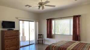 A bedroom with a bed, a dresser, a TV, a ceiling fan, and a window with curtains. - Nestled in the Superstition Mountains! Amazing views! (Apache Junction)