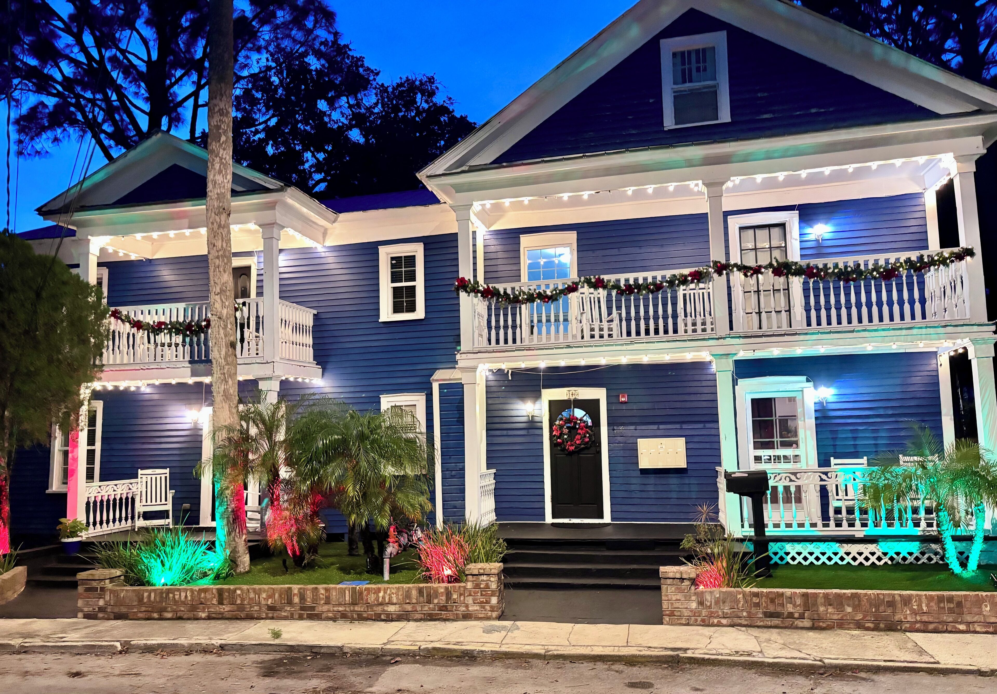 A two-story house with a porch, decorated with lights and garlands.