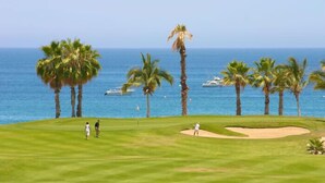 En golfbana med utsikt över havet och palmer.