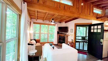 Un intérieur de chalet chaleureux avec une cheminée, un lit, un canapé et un coin repas.