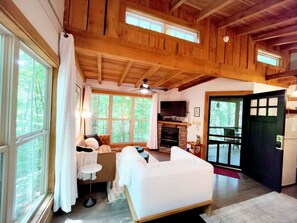 Un intérieur de chalet chaleureux avec une cheminée, un lit, un canapé et un coin repas.