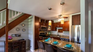 A modern kitchen with wooden cabinets, a granite countertop, and a built-in microwave. - Comfortable Condo on Turtle Bay Golf Course Sleeps 5 (Kahuku)