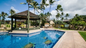 A swimming pool with three sea turtles, surrounded by palm trees and a gazebo. - Comfortable Condo on Turtle Bay Golf Course Sleeps 5 (Kahuku)