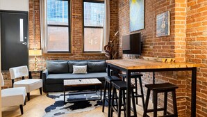 A cozy living area with a sofa, a wooden table, and bar stools. - Downtown Music City Loft living! ~Steps to the Ryman and Broadway. (Nashville)