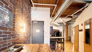 A modern kitchen with wooden flooring, a brick wall, and a metal door. - Downtown Music City Loft living! ~Steps to the Ryman and Broadway. (Nashville)