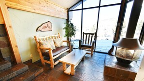 A cozy room with a wooden bench, a wooden chair, a table, and a wood-burning stove. - On Lake! Updated Penthouse! Pool, Hot Tub, Elevator. Walk to Concerts, Dining (Dillon)