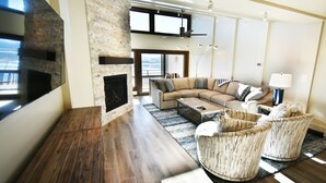 A modern living room with a fireplace, a sofa, two armchairs, a coffee table, and a TV. - On Lake! Updated Penthouse! Pool, Hot Tub, Elevator. Walk to Concerts, Dining (Dillon)