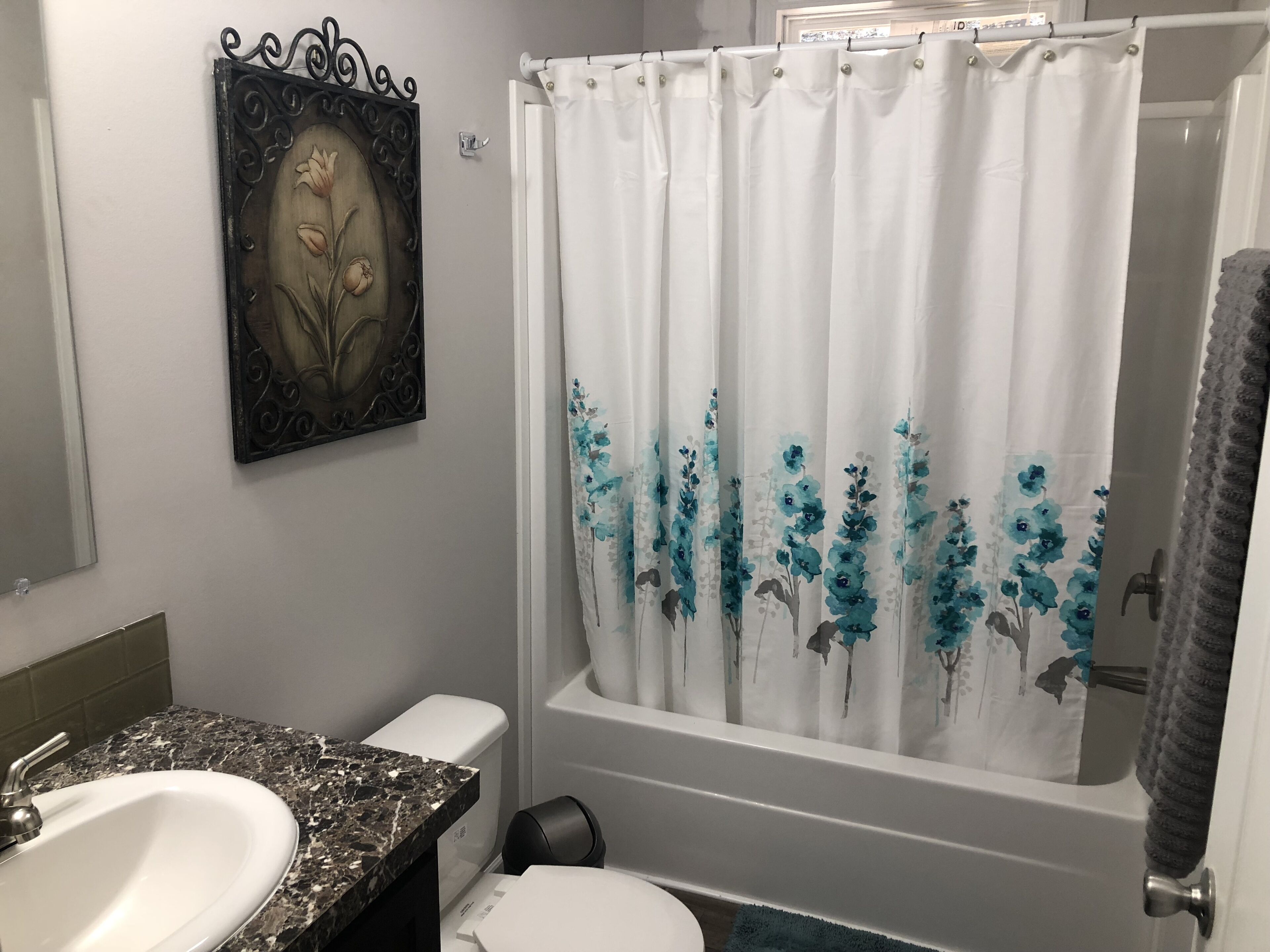A bathroom with a white sink, a toilet, a bathtub, and a shower curtain with floral patterns.