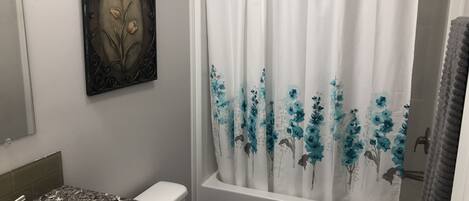 A bathroom with a white sink, a toilet, a bathtub, and a shower curtain with floral patterns.