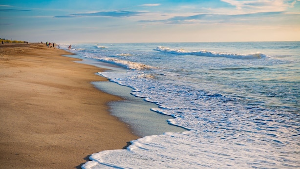 Ein Strand mit sandigem Ufer und sanften Wellen.