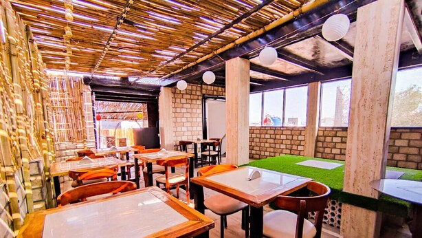 A restaurant with wooden tables and chairs, brick walls, and large windows. - Osaka Taj Hotel (Agra)