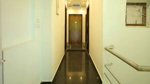 A corridor with a polished black floor, white walls, and a handrail on the right. - Osaka Taj Hotel (Agra)