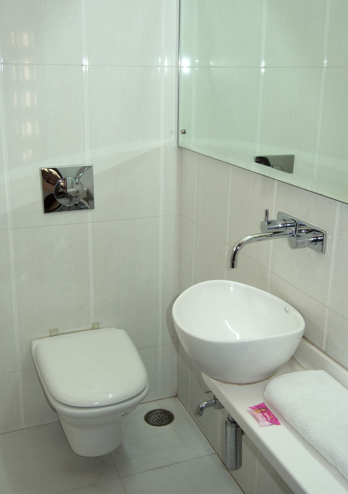 A small, clean bathroom with a toilet, sink, and mirror.