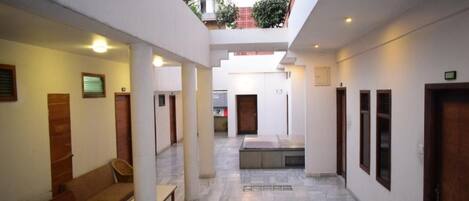 A corridor with a bench, a sofa, and a small table. There are doors and windows along the walls.