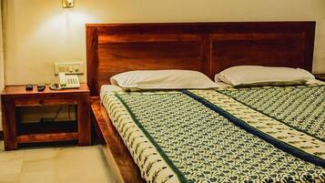 Una cama bien hecha con una colcha estampada, una mesita de noche con lámpara y un teléfono.