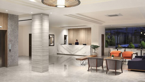 A modern hotel lobby with a reception desk, seating area, and large windows offering a view of the outdoors. - Capital O 827 Speciale Hotel (Rosario)
