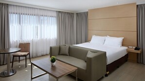 A hotel room with a large bed, a sofa, a small table, and a chair. - Capital O 827 Speciale Hotel (Rosario)