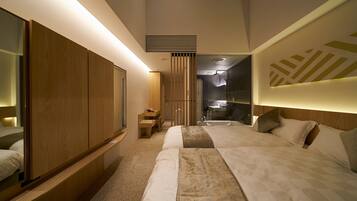 Ein modernes Hotelzimmer mit einem großen Bett, einem Holzschrank, einem kleinen Schreibtisch und einem Badezimmer mit Dusche und Waschbecken.