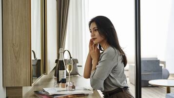 A woman sitting at a wooden desk with a bottle of wine, a glass, and some books.