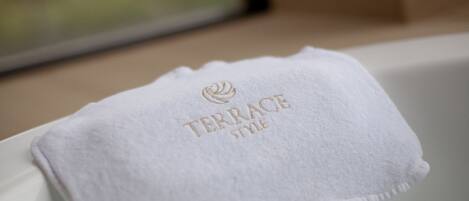 Ein weißes Handtuch mit goldsticktem Schriftzug "TERRACE" auf einem weißen Stuhl.