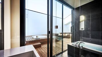 A modern bathroom with a glass-enclosed shower, a bathtub, and a wooden deck area visible through the glass doors.