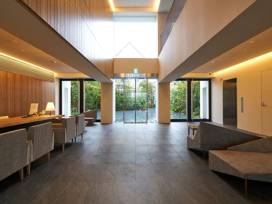Eine geräumige Lobby mit einer Rezeption, einer Sitzecke und großen Fenstern mit Blick ins Freie.