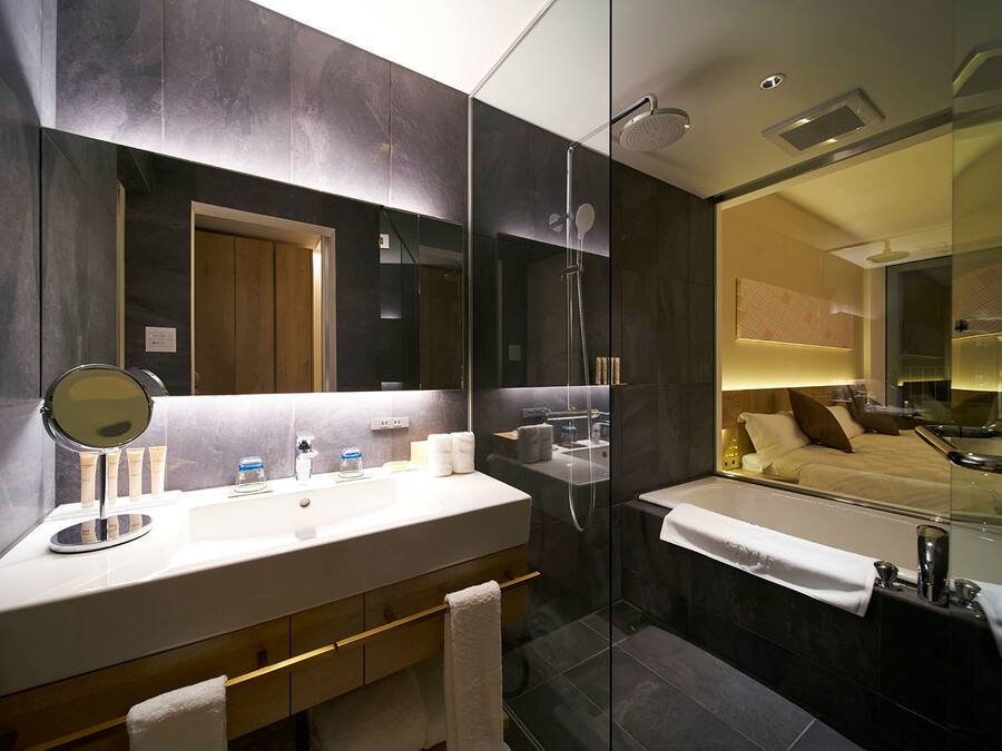 Un bagno moderno con uno specchio grande, una doccia e una vasca da bagno.