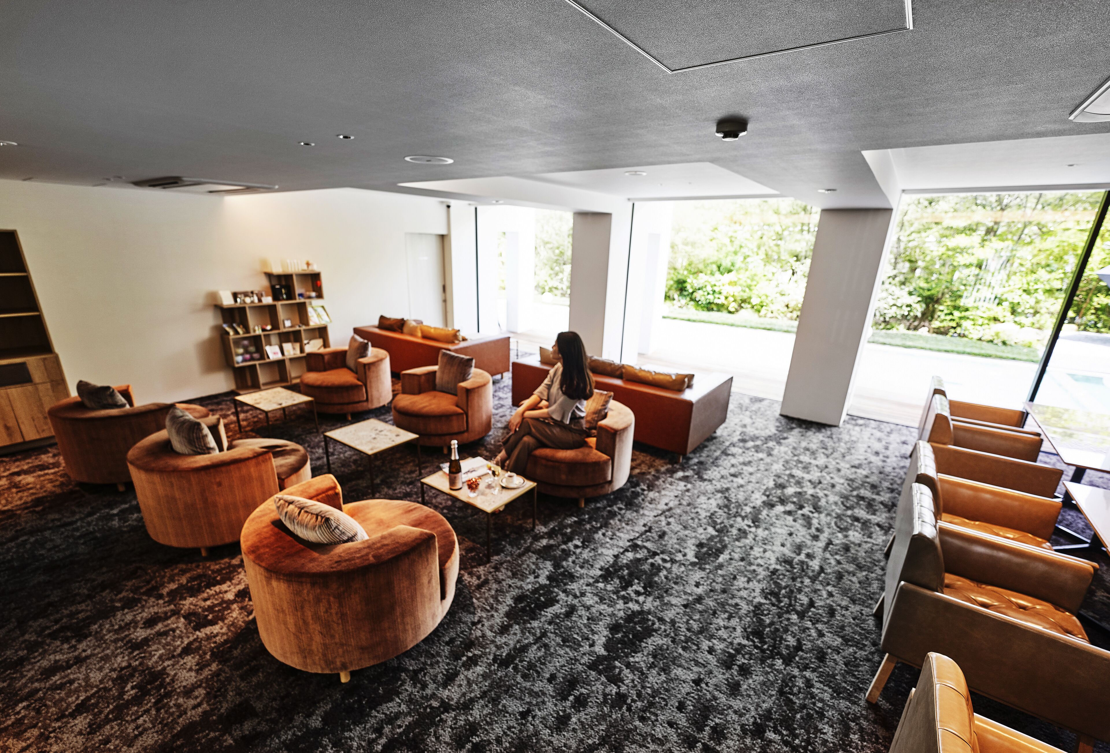 A modern lounge area with leather sofas, a coffee table, and a bookshelf.