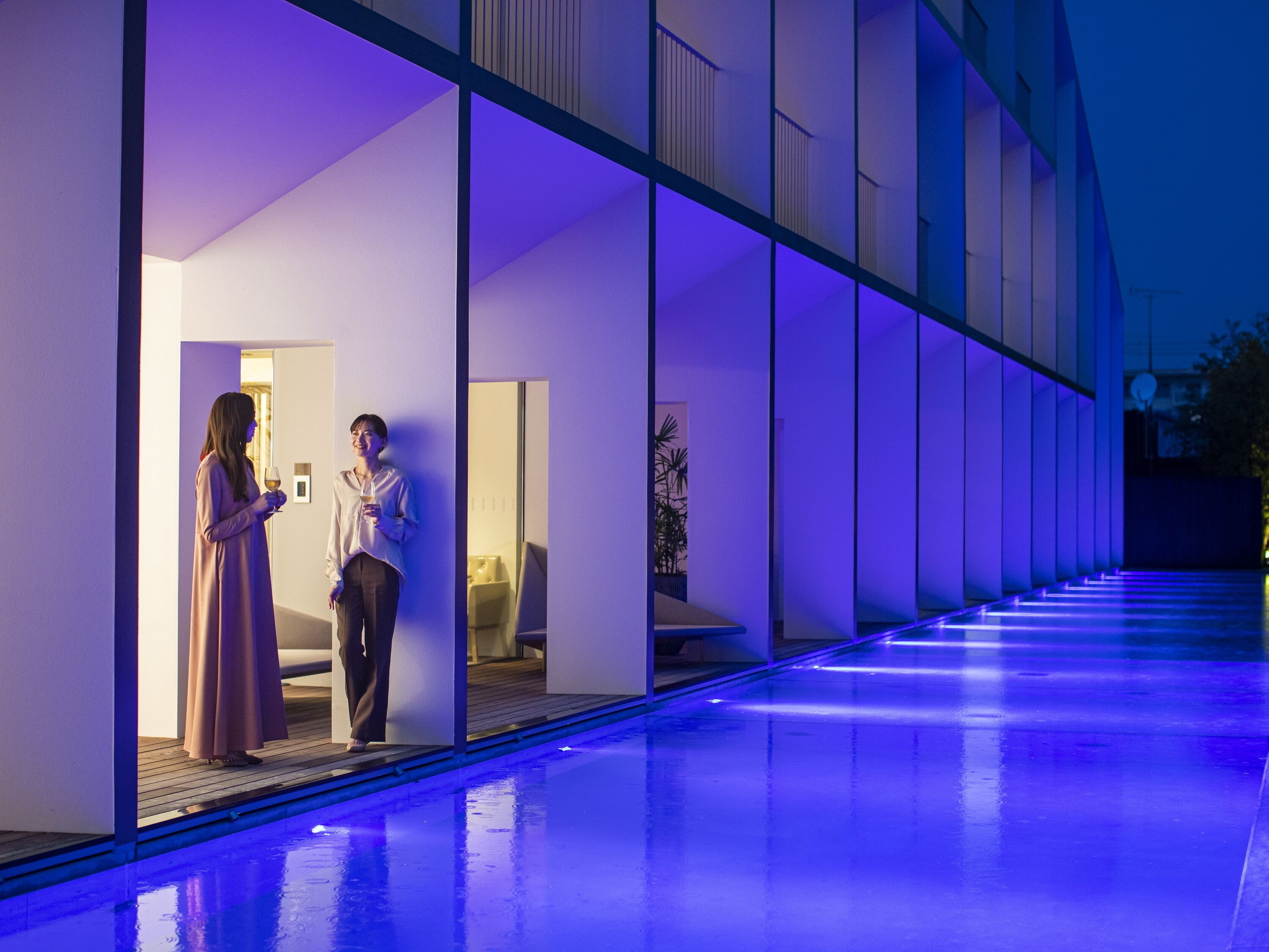 A modern building with a glass facade and a pool area.