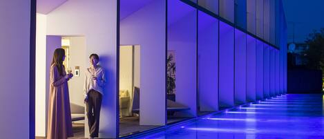 A modern building with a glass facade and a pool area.